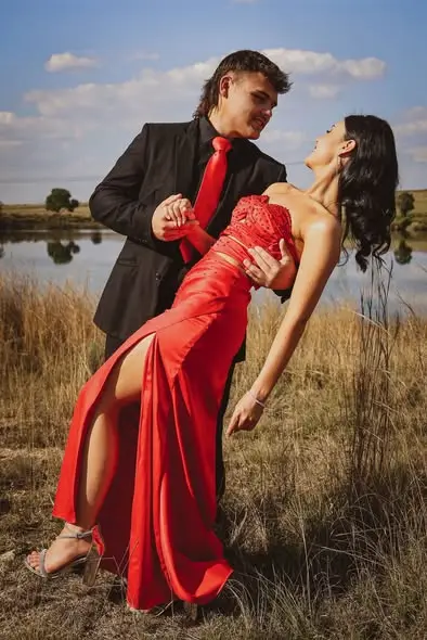 A couple dancing in a field, her red dress swinging