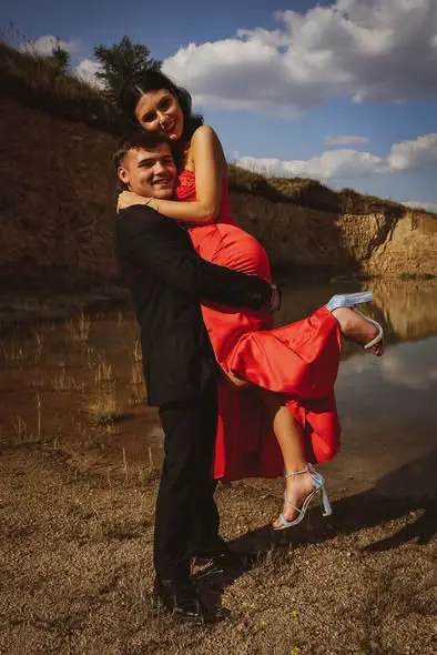 A groom lifting his partner in a red dress