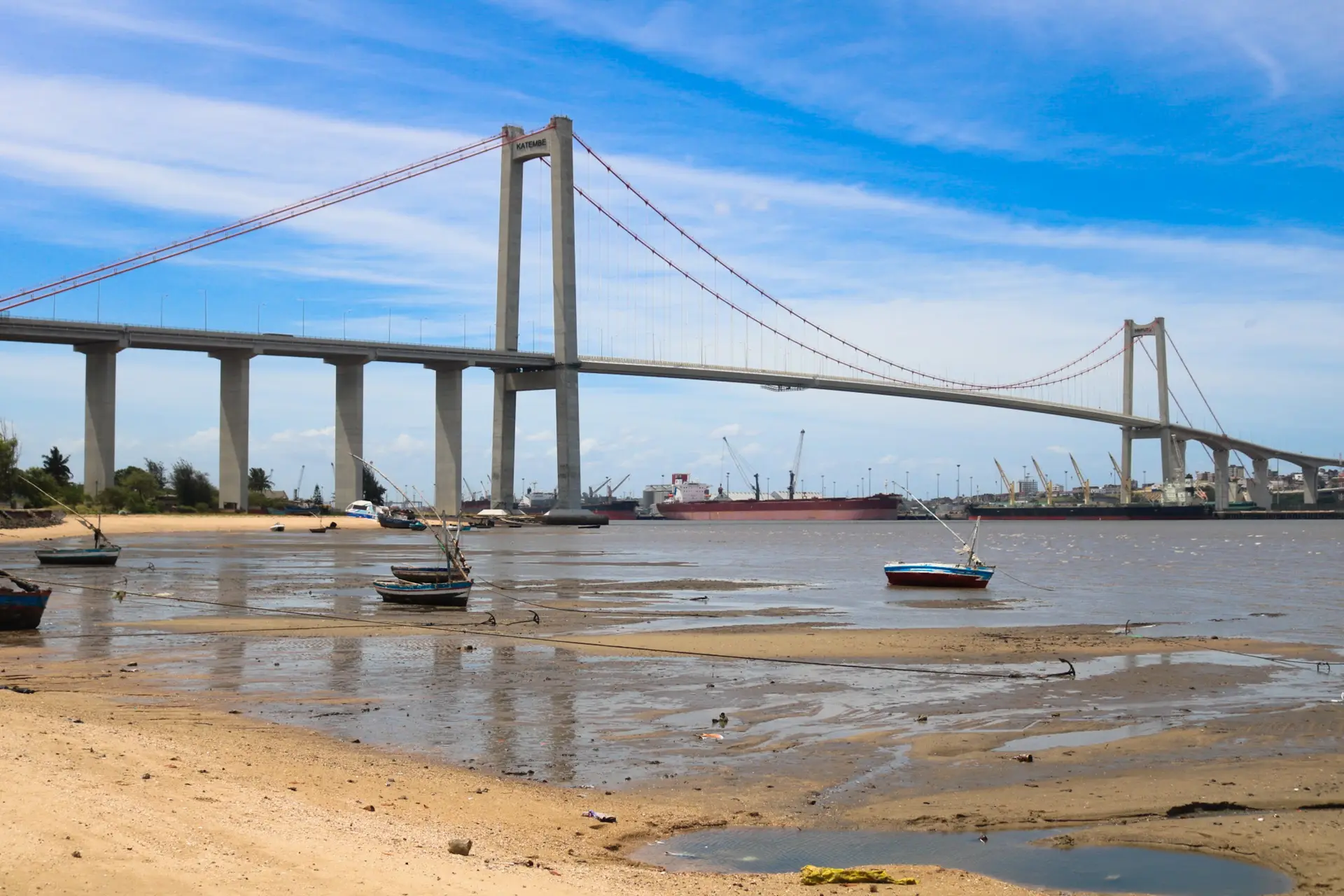 A suspension bridge over a harbour at low tide